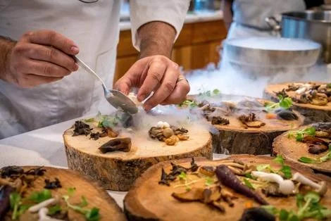 Chef's hands decorating a plate of food.