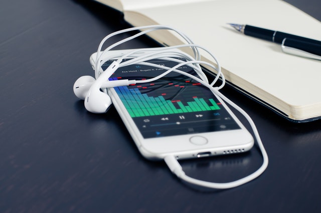 A white phone with earphones connected.