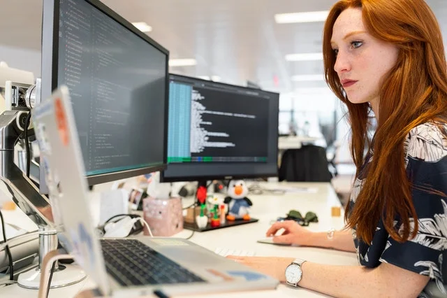 Female computer scientist working in front of screens.