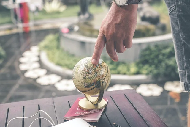 Finger pointing study abroad destination on a globe.