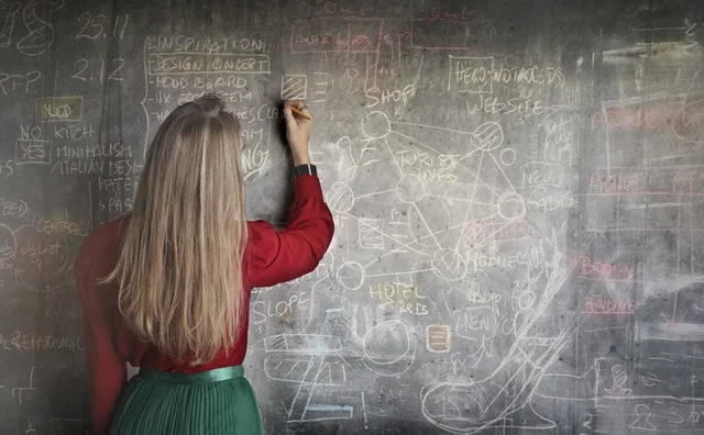 Fresh graduate teacher writing on black board.