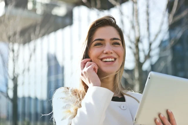 Business management student smiling holding a phone.