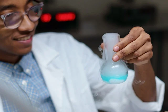 Male chemical engineer holding round bottomed flask.