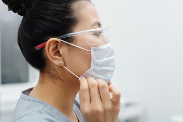 A nurse wearing eye shield and face mask.