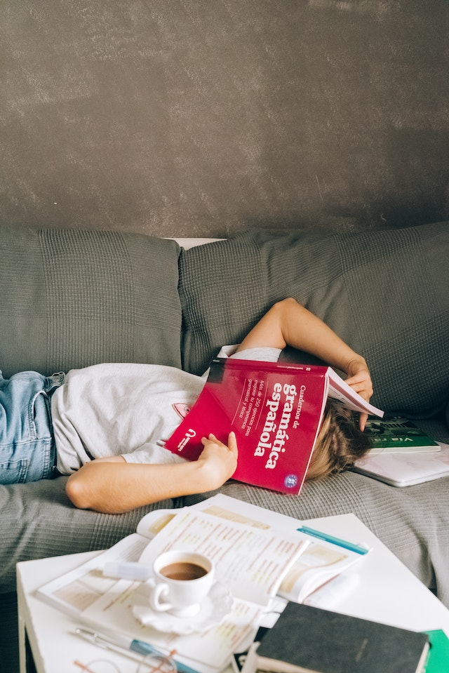 Student falling asleep with book on face.